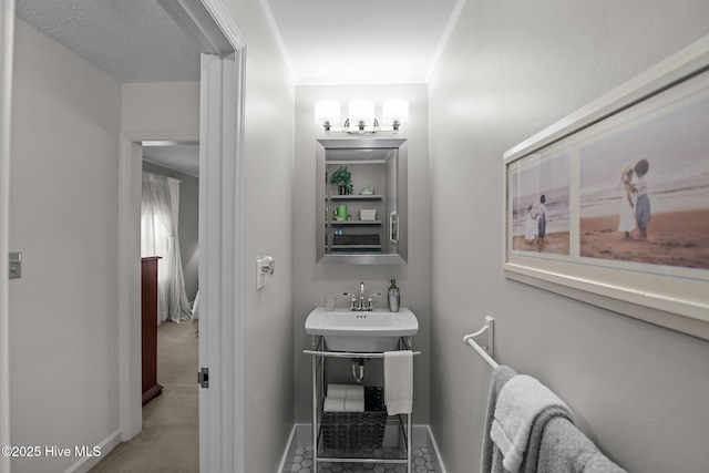 bathroom with a sink, baseboards, and ornamental molding