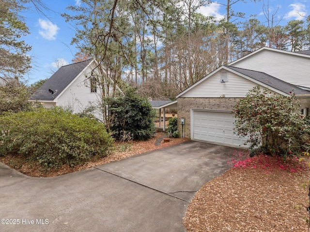 view of home's exterior with concrete driveway, a garage, brick siding, and a shingled roof