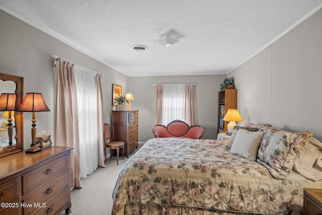 bedroom with a textured ceiling, ornamental molding, visible vents, and light carpet