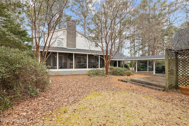 rear view of property with a sunroom and a chimney