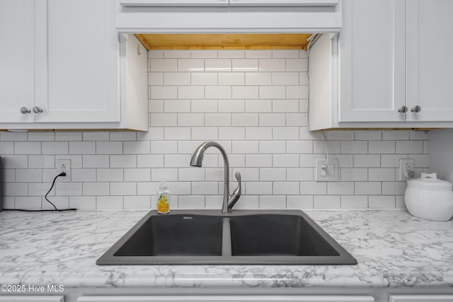 kitchen with white cabinetry, custom exhaust hood, tasteful backsplash, and a sink