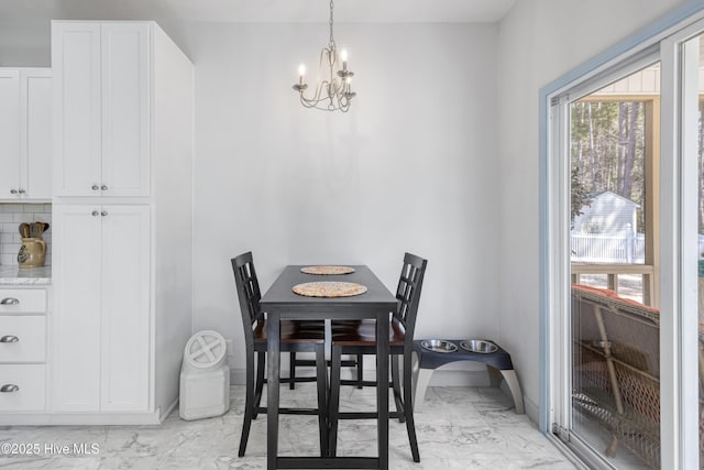 dining room with a chandelier, marble finish floor, and baseboards