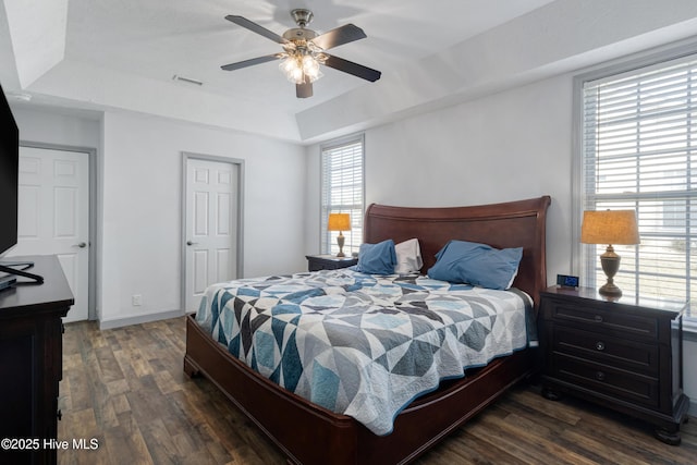 bedroom featuring visible vents, a raised ceiling, dark wood finished floors, and a ceiling fan