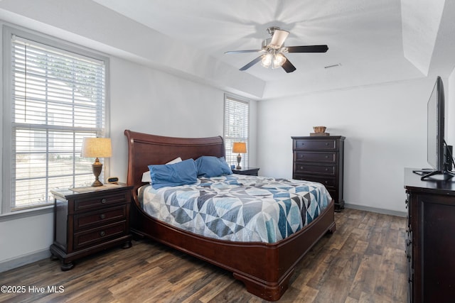 bedroom featuring a tray ceiling, baseboards, and dark wood-style flooring