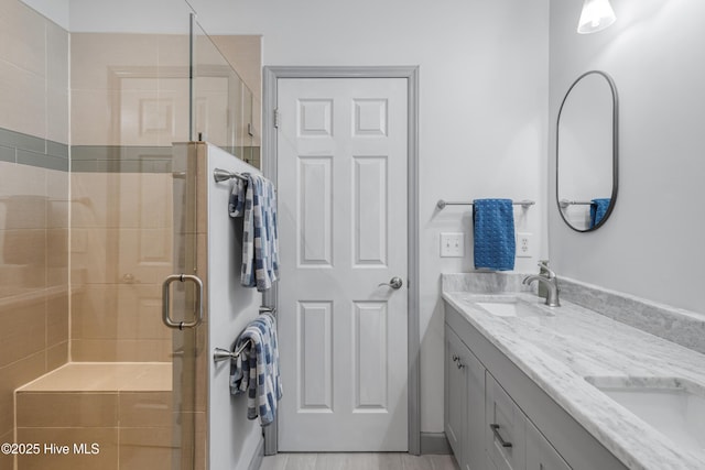full bath with double vanity, a shower stall, and a sink