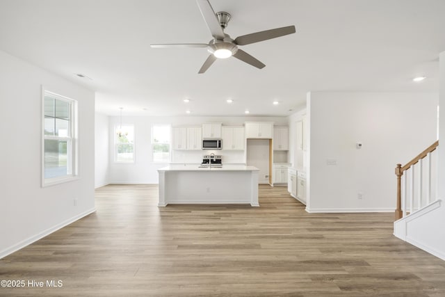 kitchen featuring recessed lighting, stainless steel microwave, white cabinets, and light wood-style flooring