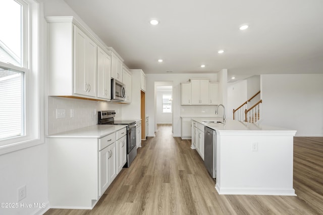 kitchen featuring a sink, light wood-style floors, appliances with stainless steel finishes, white cabinets, and light countertops