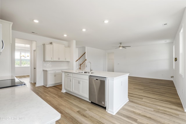 kitchen with stainless steel dishwasher, light countertops, light wood-style floors, and a sink