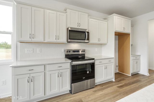 kitchen with backsplash, light wood-type flooring, light countertops, appliances with stainless steel finishes, and white cabinets