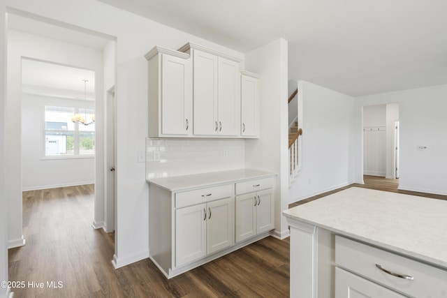 kitchen featuring backsplash, baseboards, light countertops, white cabinetry, and dark wood-style flooring