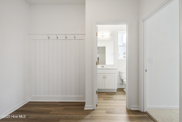 mudroom featuring a sink, baseboards, and wood finished floors