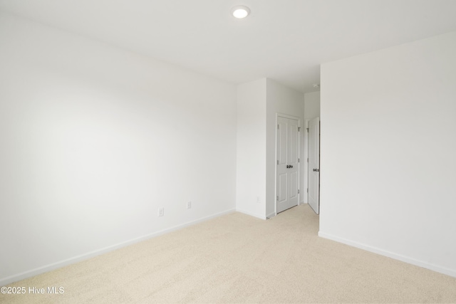 unfurnished room featuring baseboards and light carpet