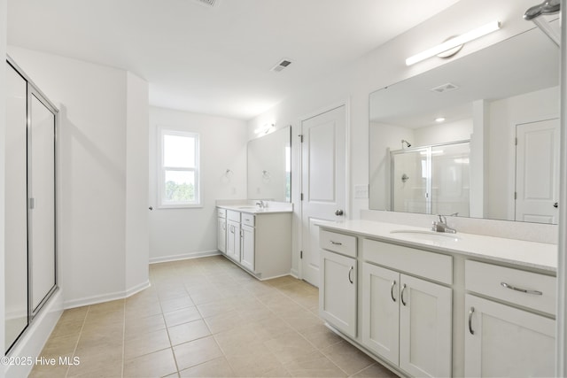 bathroom with visible vents, a shower stall, two vanities, and a sink