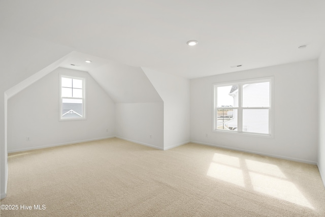 bonus room featuring lofted ceiling, visible vents, baseboards, and light carpet