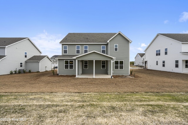 back of house featuring a yard, a shingled roof, and a patio