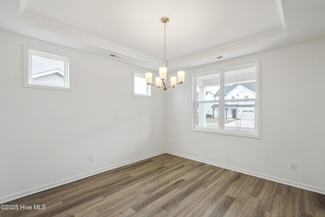 empty room with visible vents, baseboards, ornamental molding, wood finished floors, and a raised ceiling