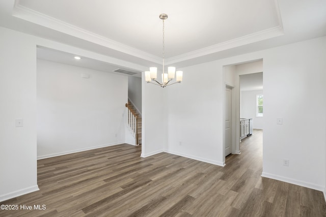 spare room with stairway, wood finished floors, visible vents, baseboards, and ornamental molding