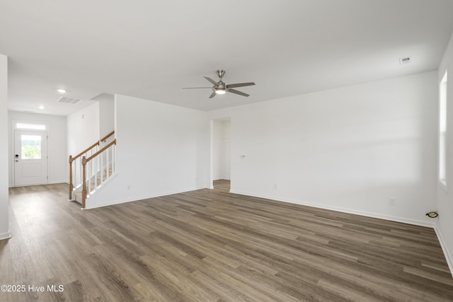 spare room with visible vents, stairs, baseboards, and wood finished floors