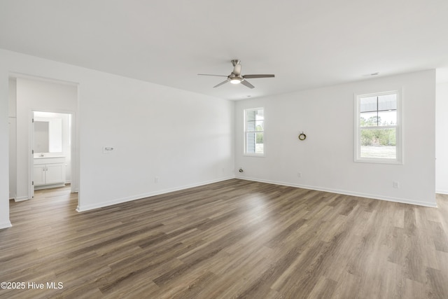 unfurnished room with a ceiling fan, wood finished floors, and baseboards