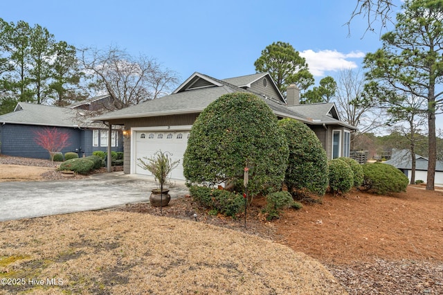 view of front of house with a chimney, an attached garage, concrete driveway, and roof with shingles