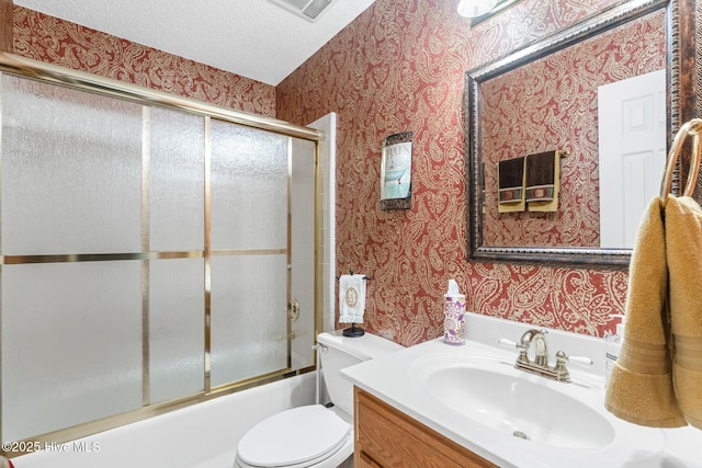 full bathroom featuring vanity, wallpapered walls, bath / shower combo with glass door, a textured ceiling, and toilet