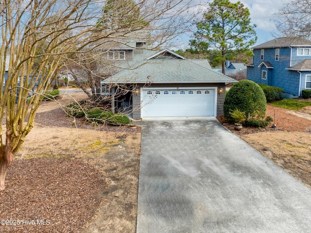 traditional-style home with roof with shingles, concrete driveway, and an attached garage