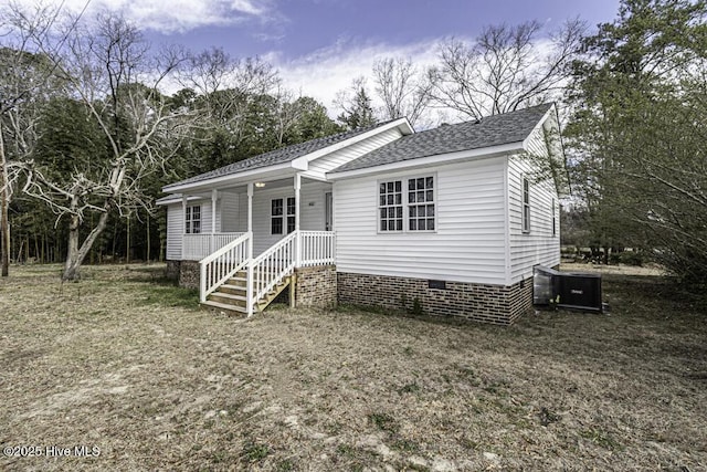 view of front of home with crawl space, covered porch, a shingled roof, and central AC