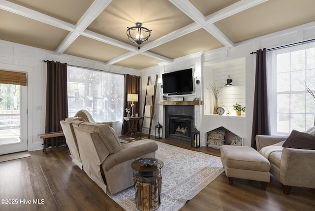 living area featuring dark wood-type flooring, a fireplace with flush hearth, coffered ceiling, and beam ceiling