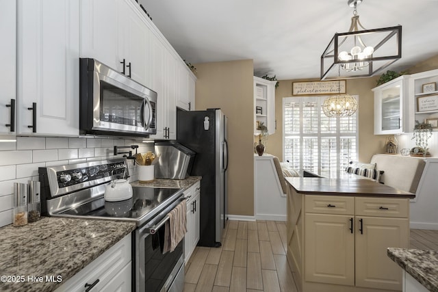 kitchen featuring backsplash, appliances with stainless steel finishes, white cabinetry, and an inviting chandelier