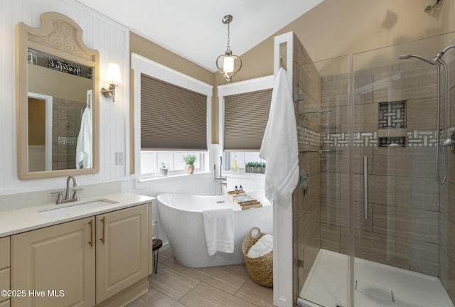 bathroom with a freestanding bath, a stall shower, vanity, and vaulted ceiling