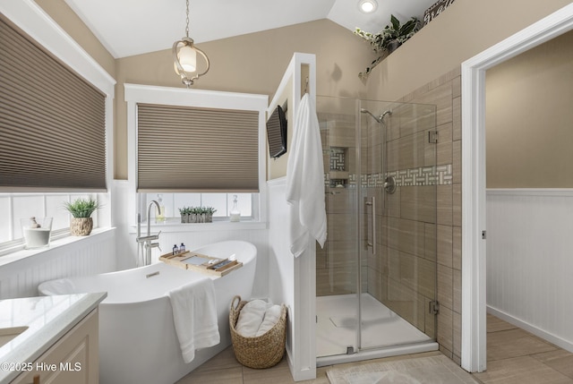 full bath with a wainscoted wall, a shower stall, lofted ceiling, a soaking tub, and vanity