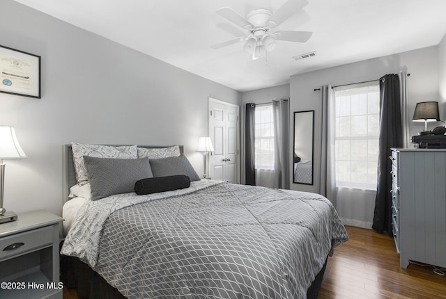 bedroom featuring dark wood-style floors, visible vents, and ceiling fan