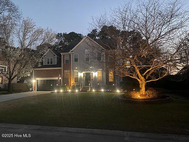 traditional home with driveway, an attached garage, and a front lawn