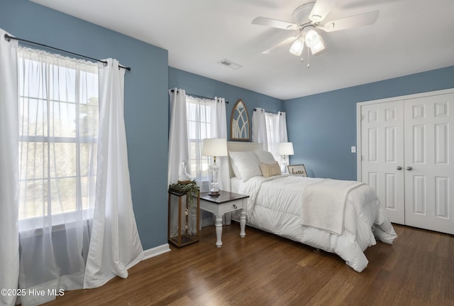 bedroom with wood finished floors, baseboards, visible vents, ceiling fan, and a closet