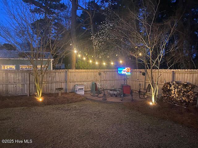 yard at twilight featuring a patio, an outdoor fire pit, and a fenced backyard