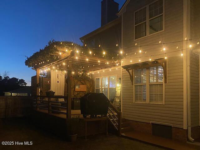 property exterior at night with fence and a chimney