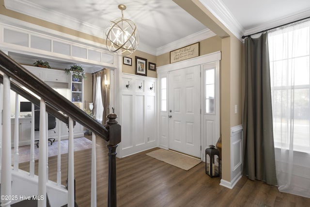 entrance foyer with a chandelier, a decorative wall, dark wood-style flooring, and ornamental molding