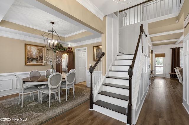 dining room with dark wood-type flooring, a notable chandelier, stairway, crown molding, and a decorative wall