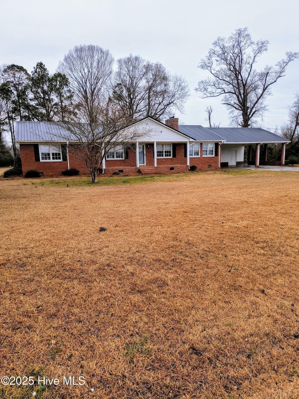 ranch-style house with brick siding, a front lawn, a carport, a chimney, and crawl space