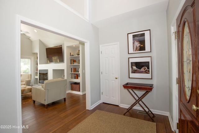 interior space featuring baseboards, high vaulted ceiling, and dark wood-style floors