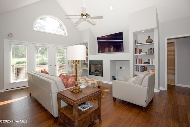 living area with dark wood finished floors, built in shelves, high vaulted ceiling, and a ceiling fan