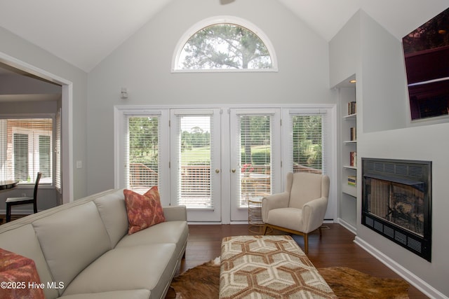 living room with plenty of natural light, dark wood-type flooring, built in shelves, and a fireplace