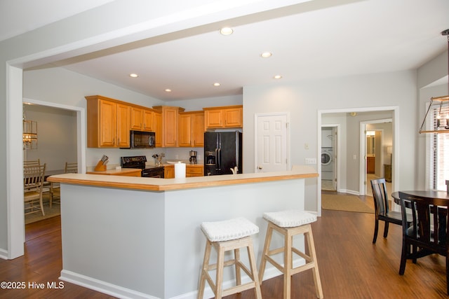 kitchen with dark wood finished floors, recessed lighting, washer / dryer, and black appliances