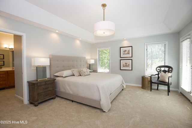 bedroom featuring multiple windows, light carpet, and a raised ceiling