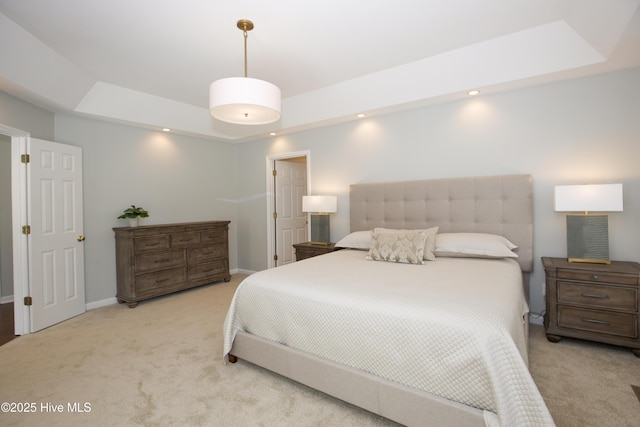 bedroom with recessed lighting, a tray ceiling, baseboards, and carpet