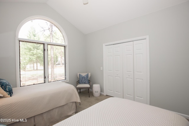 carpeted bedroom with a closet and lofted ceiling