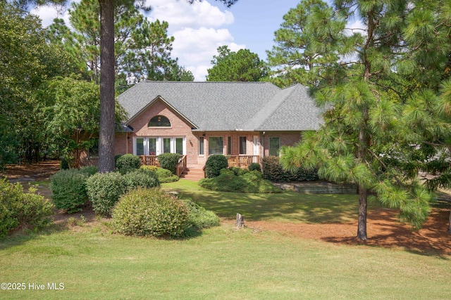 view of front of home featuring a front yard, brick siding, and roof with shingles