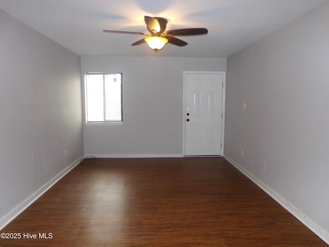 empty room with baseboards, dark wood-style floors, and a ceiling fan