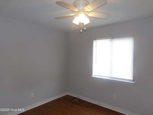 unfurnished room with dark wood finished floors, a ceiling fan, and baseboards