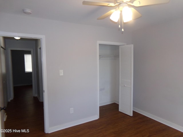 unfurnished bedroom with ceiling fan, wood finished floors, a closet, and baseboards